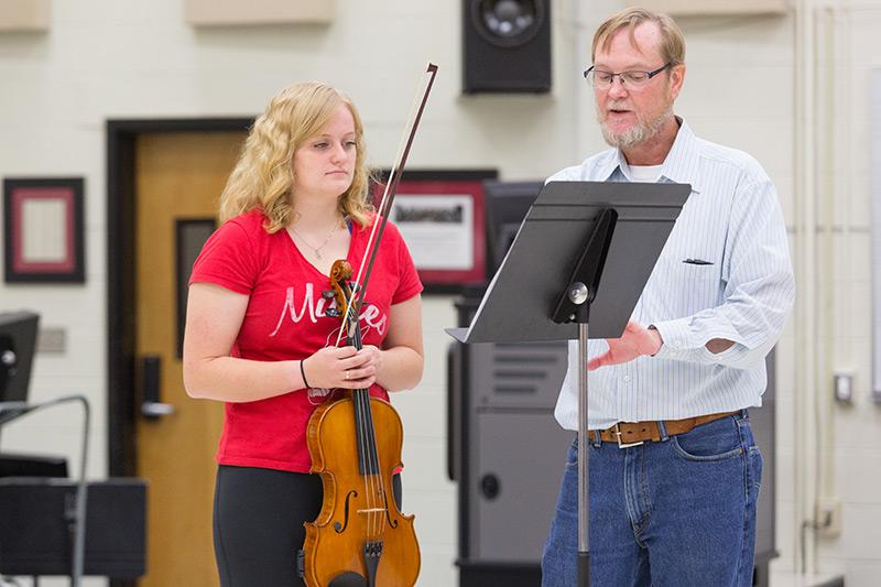 Professor working with a student holding a violin