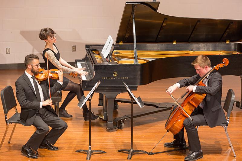 Orchestra students playing string instruments and piano