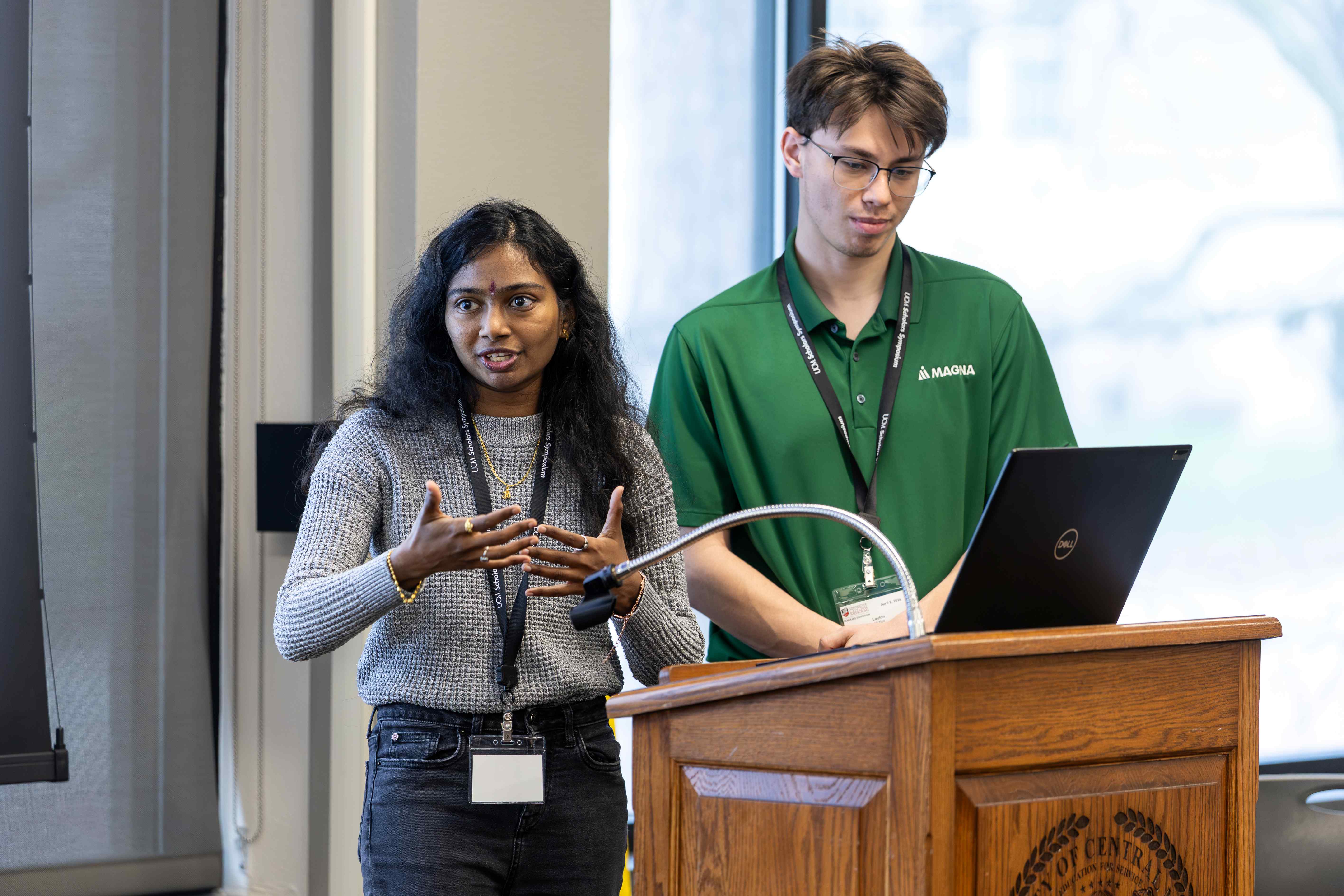 Two students behind a podium and computer presenting their research.