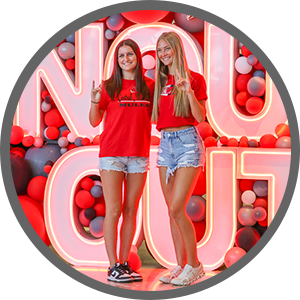 Two students standing in from of  'Snouts Out' sign