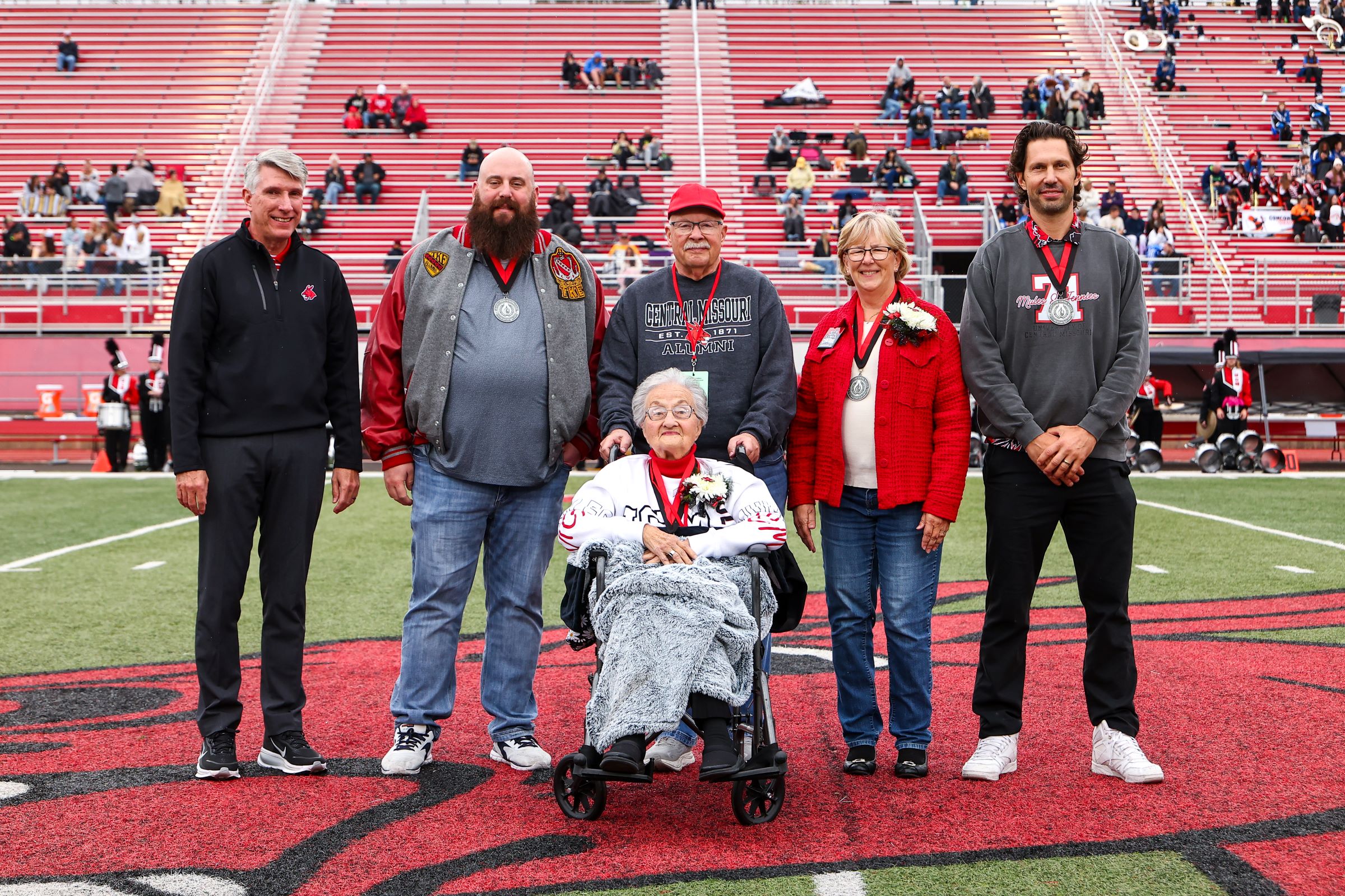 UCM President Roger Best with the 2025 Distinguished Alumni Award recipients at halftime