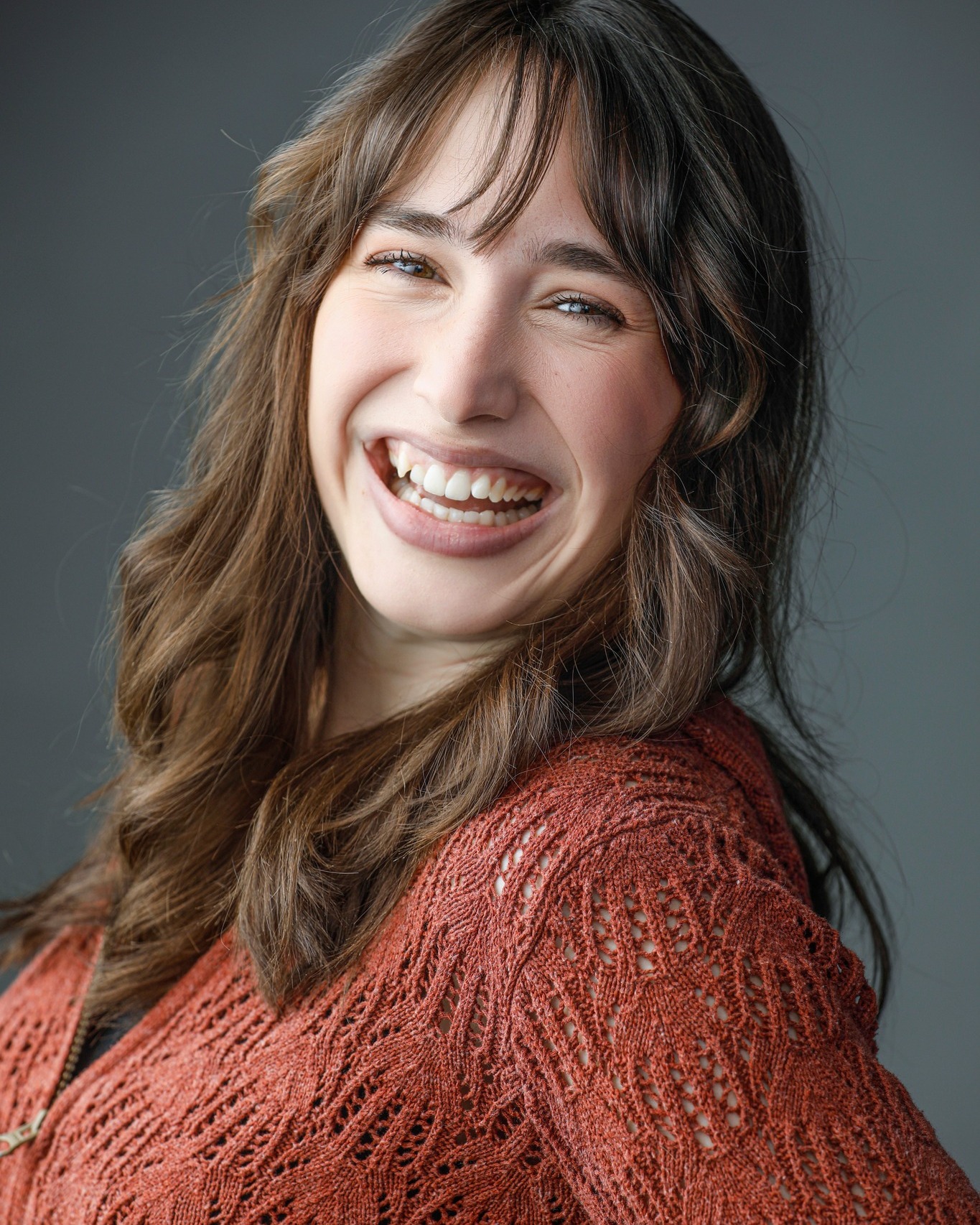 A smiling young woman is seen in a portrait from the shoulders up.