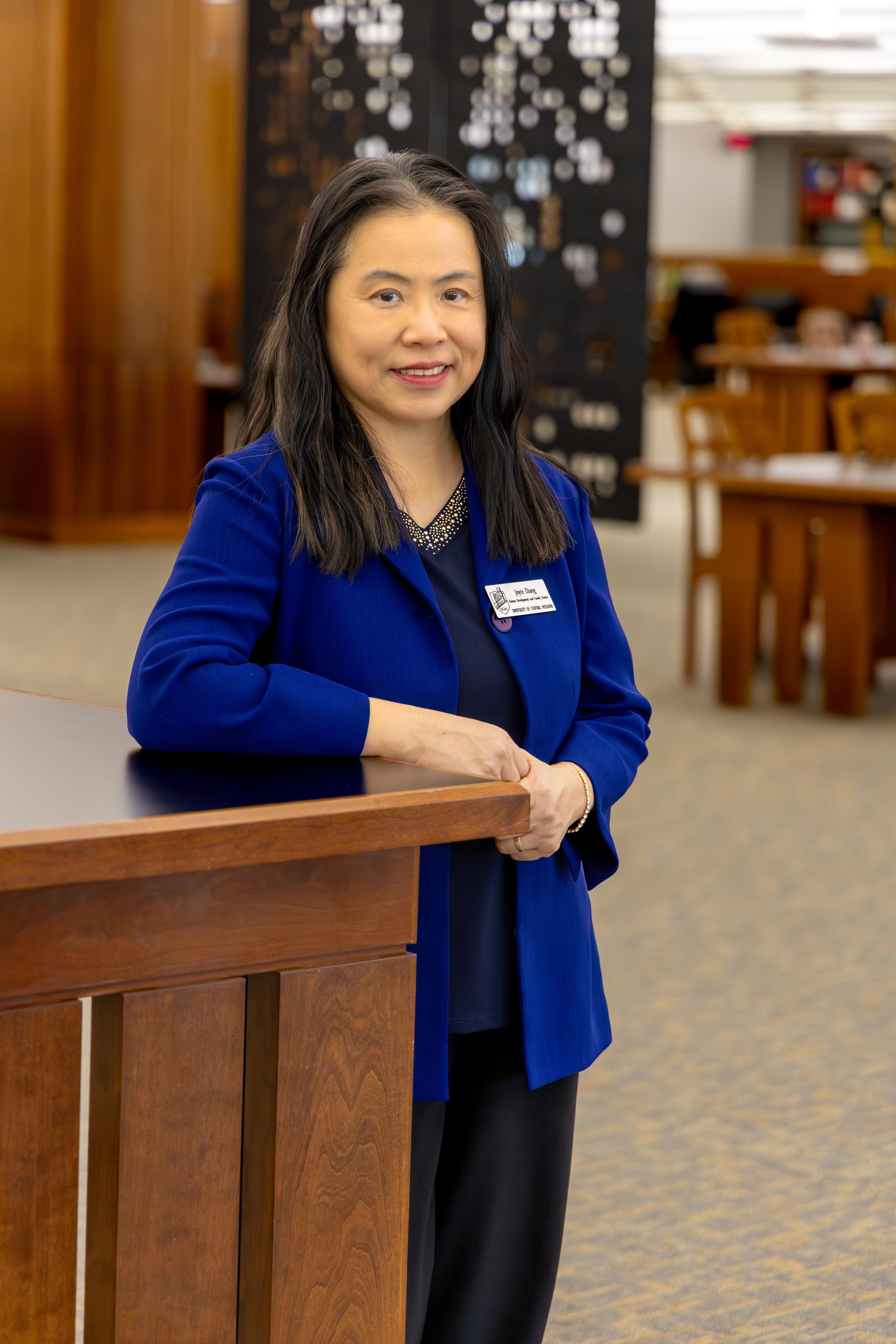 Joyce Chang stands in the James C. Kirkpatrick Library with her arm resting on a tall table.