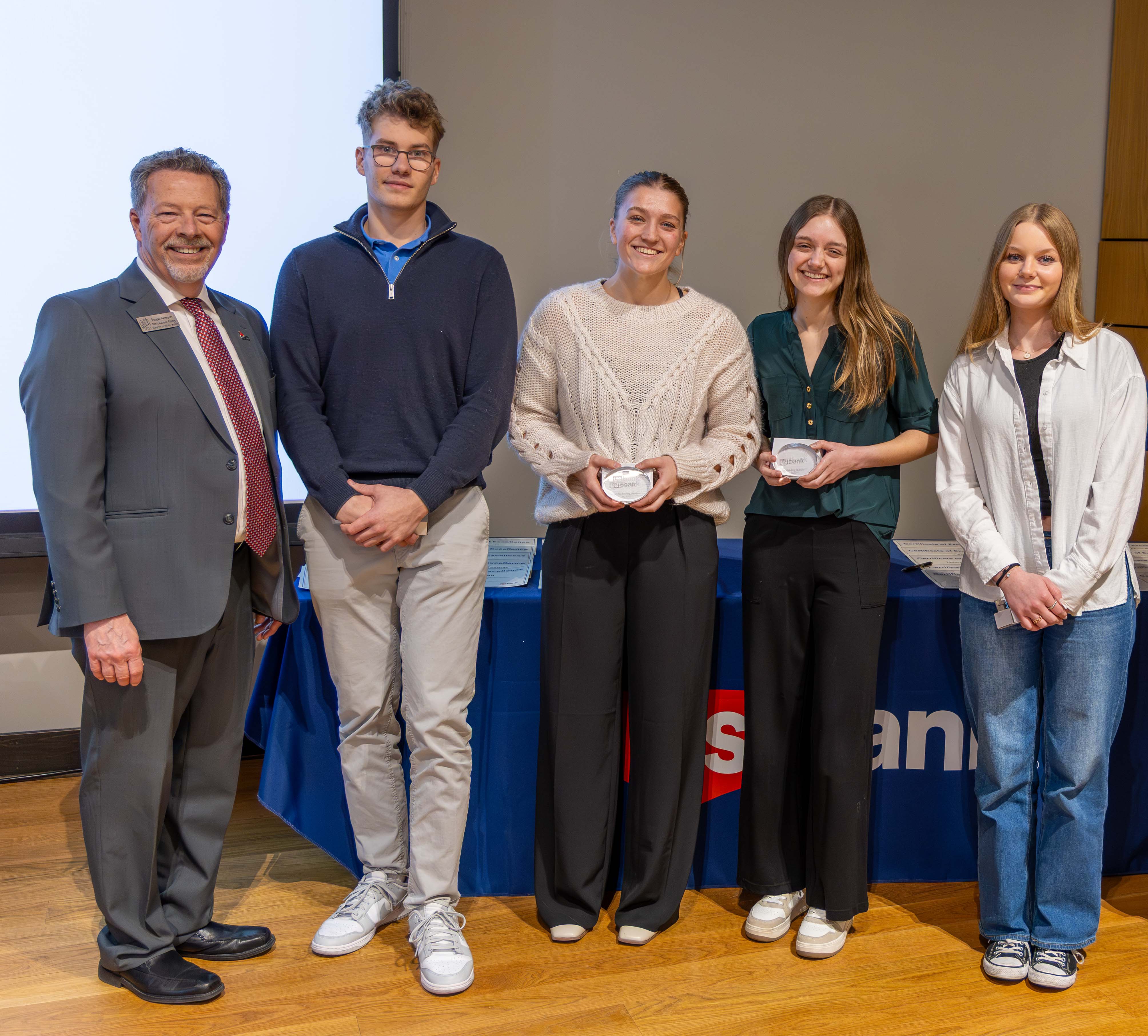 Five people stand in a row on a stage