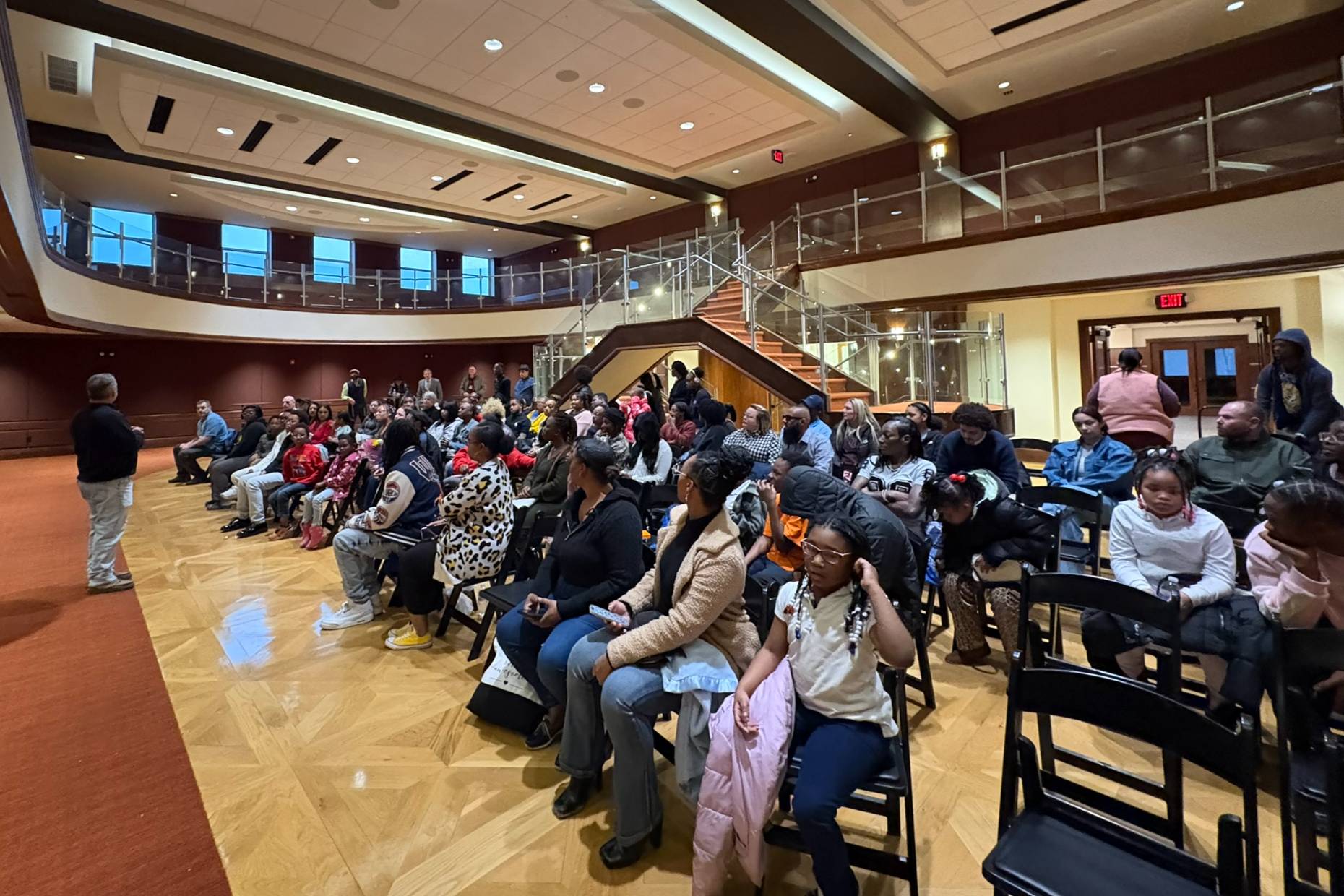 A person addresses a crowd in an auditorium during a graduation ceremony