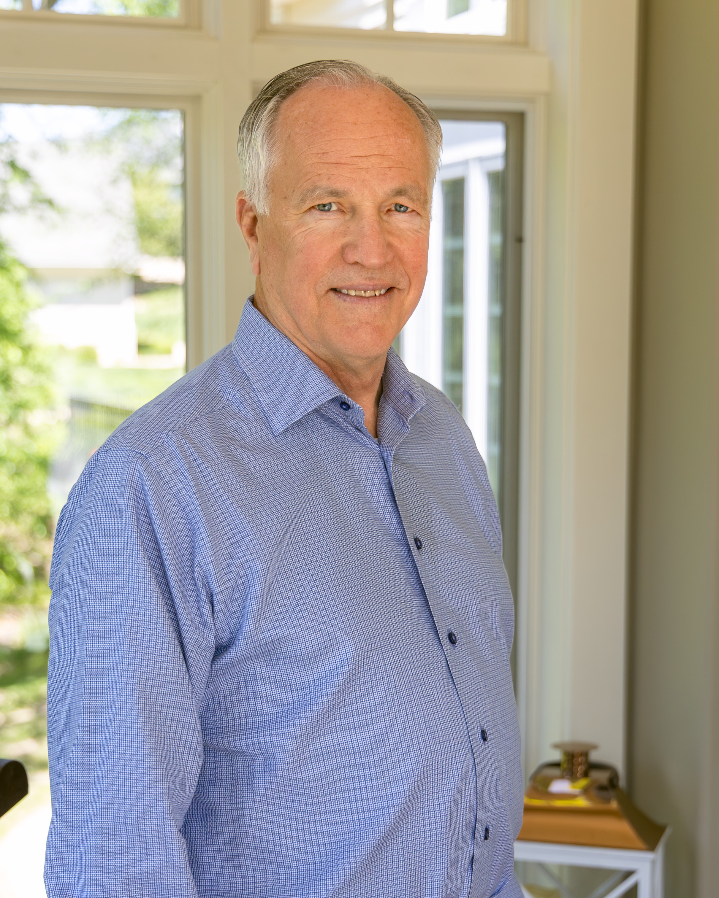 Kevin Visser Kevin Visser is seen in a professional portrait from the shoulders up. Kevin has short gray hair and is wearing a blue button-up shirt. He is standing in front of a window overlooking trees.