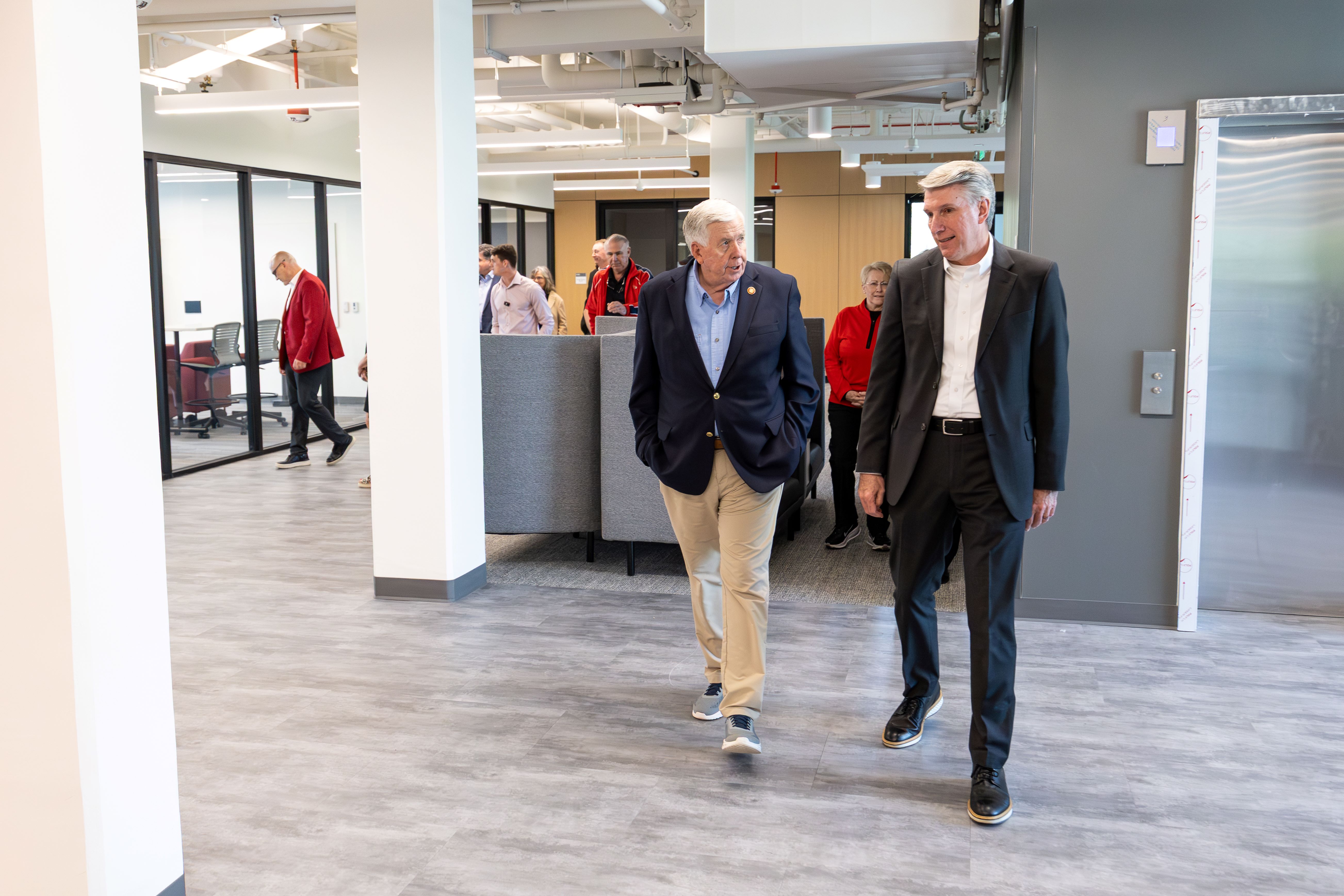 President Best and former Gov. Mike Parson walk through an open area in the Humphreys Building while several people are behind them. The two men are talking to each other as the other people are looking at details in the newly renovated space.