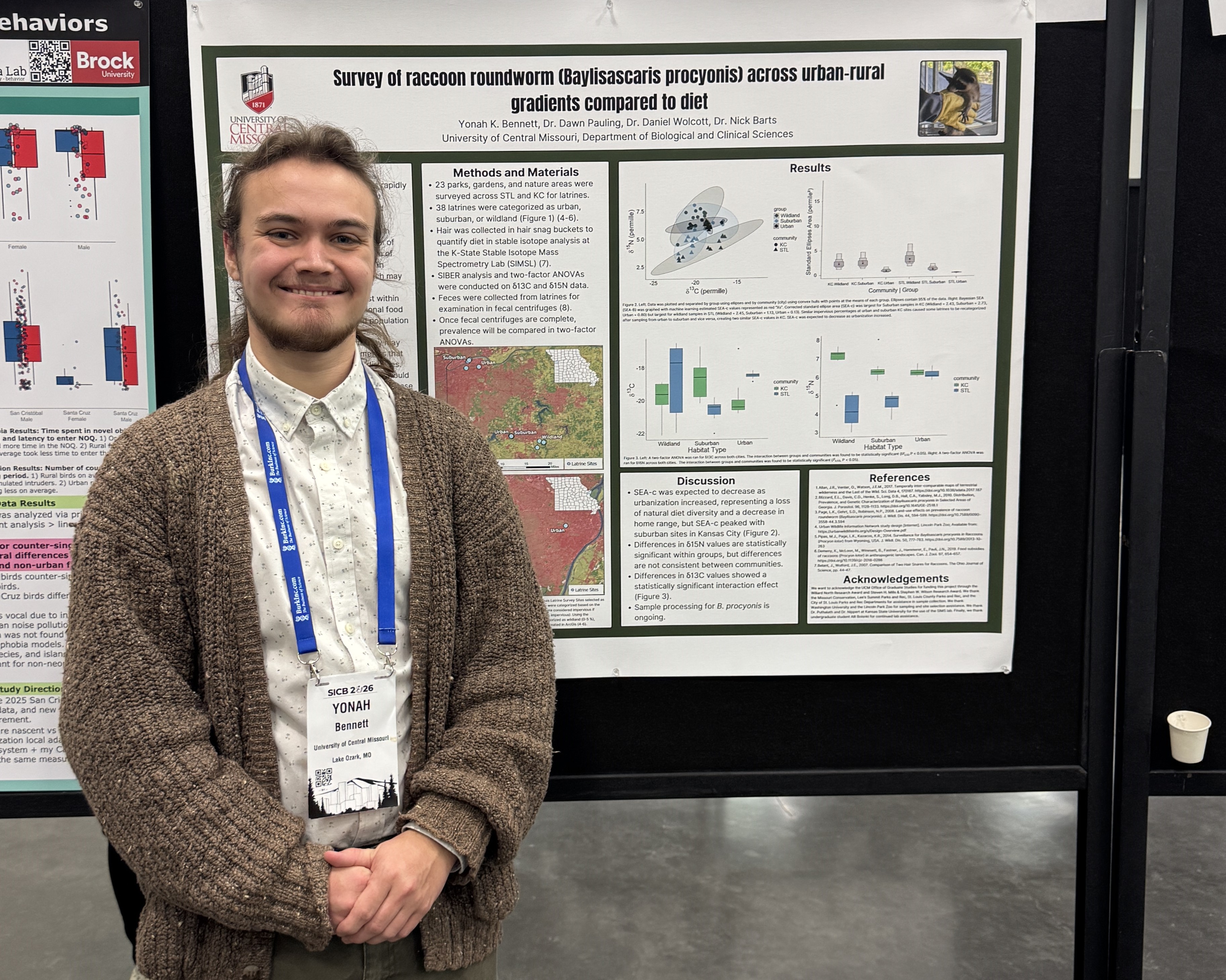A student stands in front of their research poster