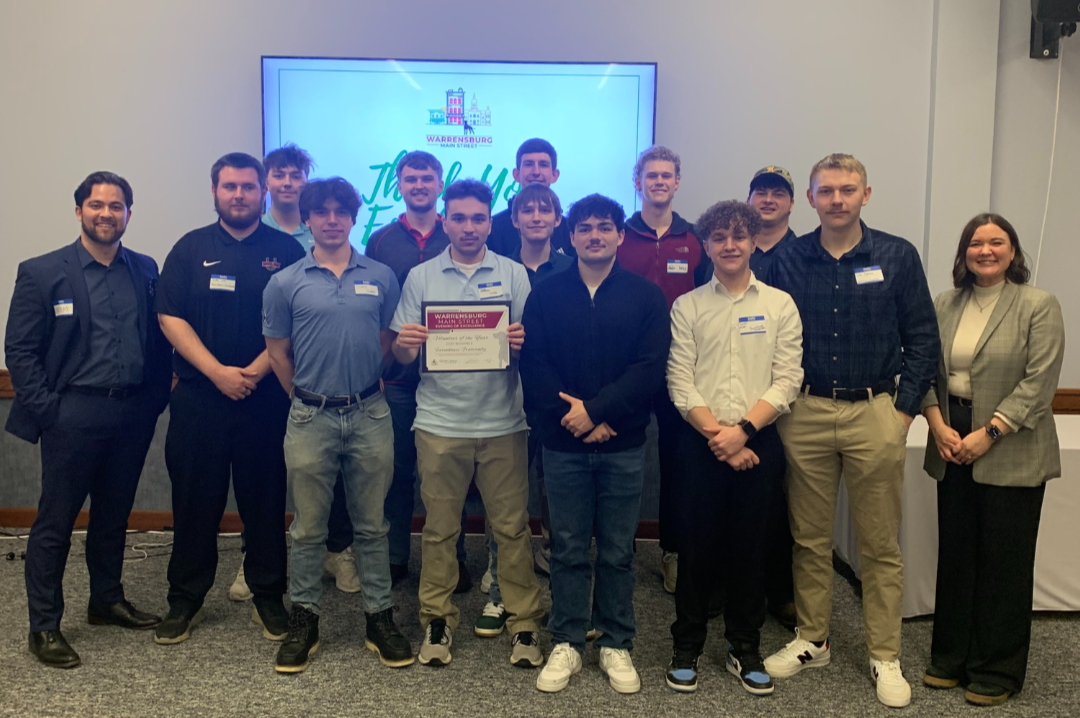 Fraternity members stand with the Warrensburg Main Street director