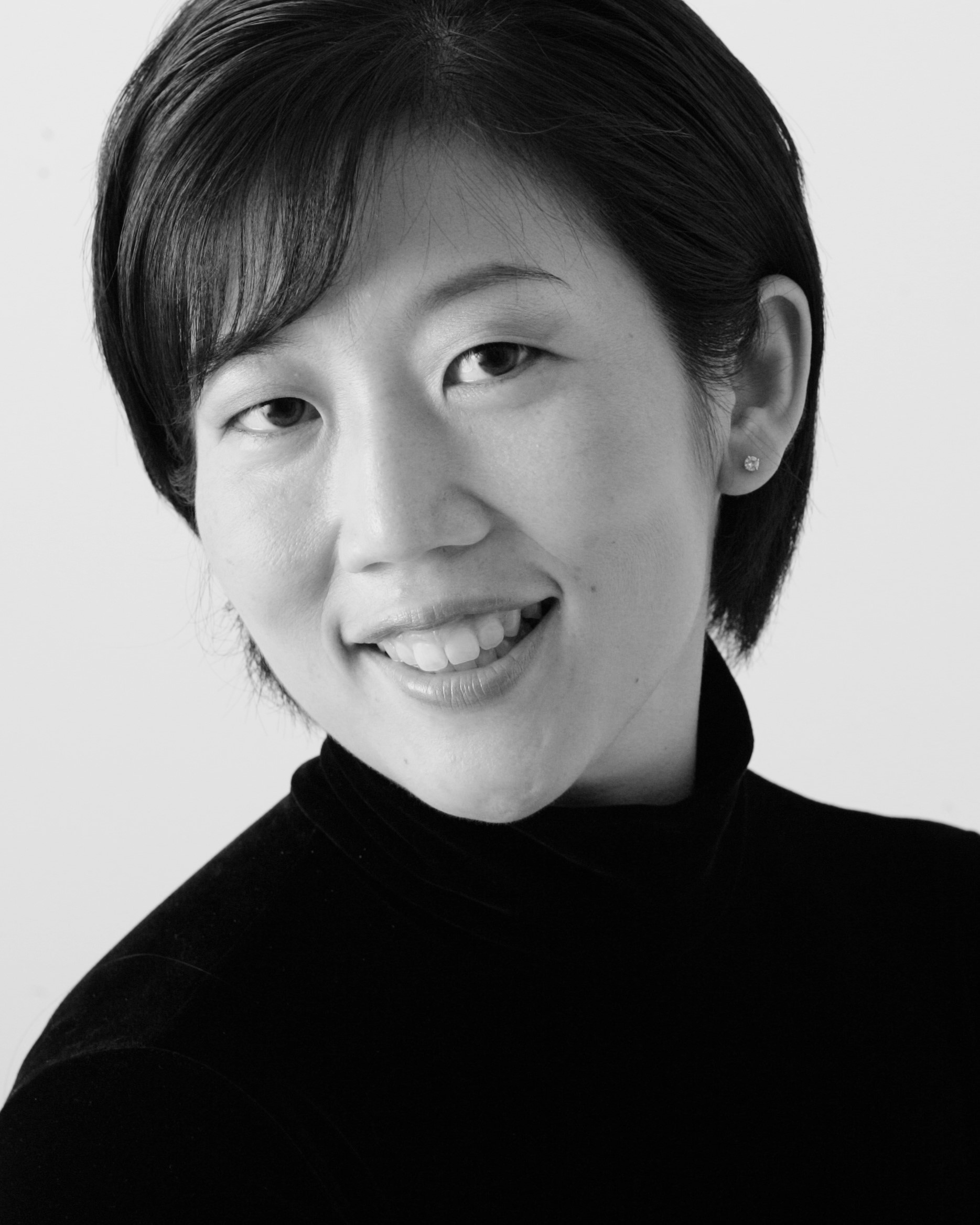 A woman poses for a portrait and is seen in black and white from the shoulders up