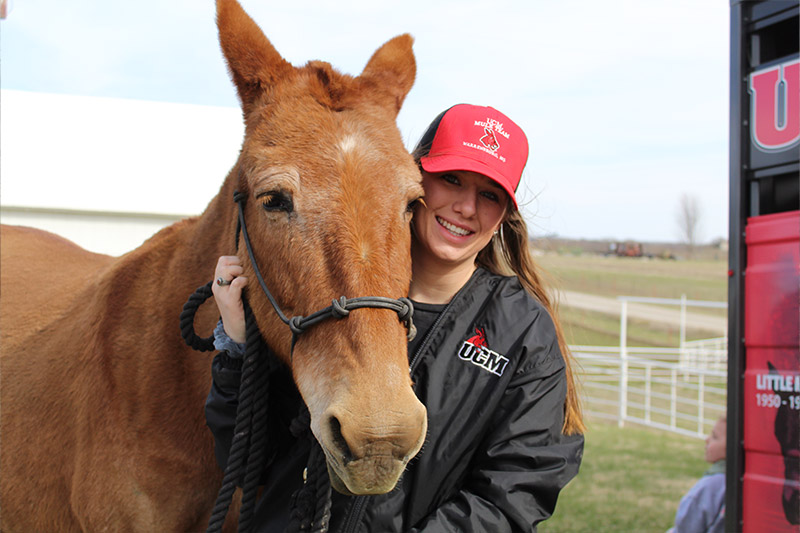 A student posing with a mule