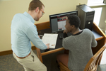 man helping student sitting at computer