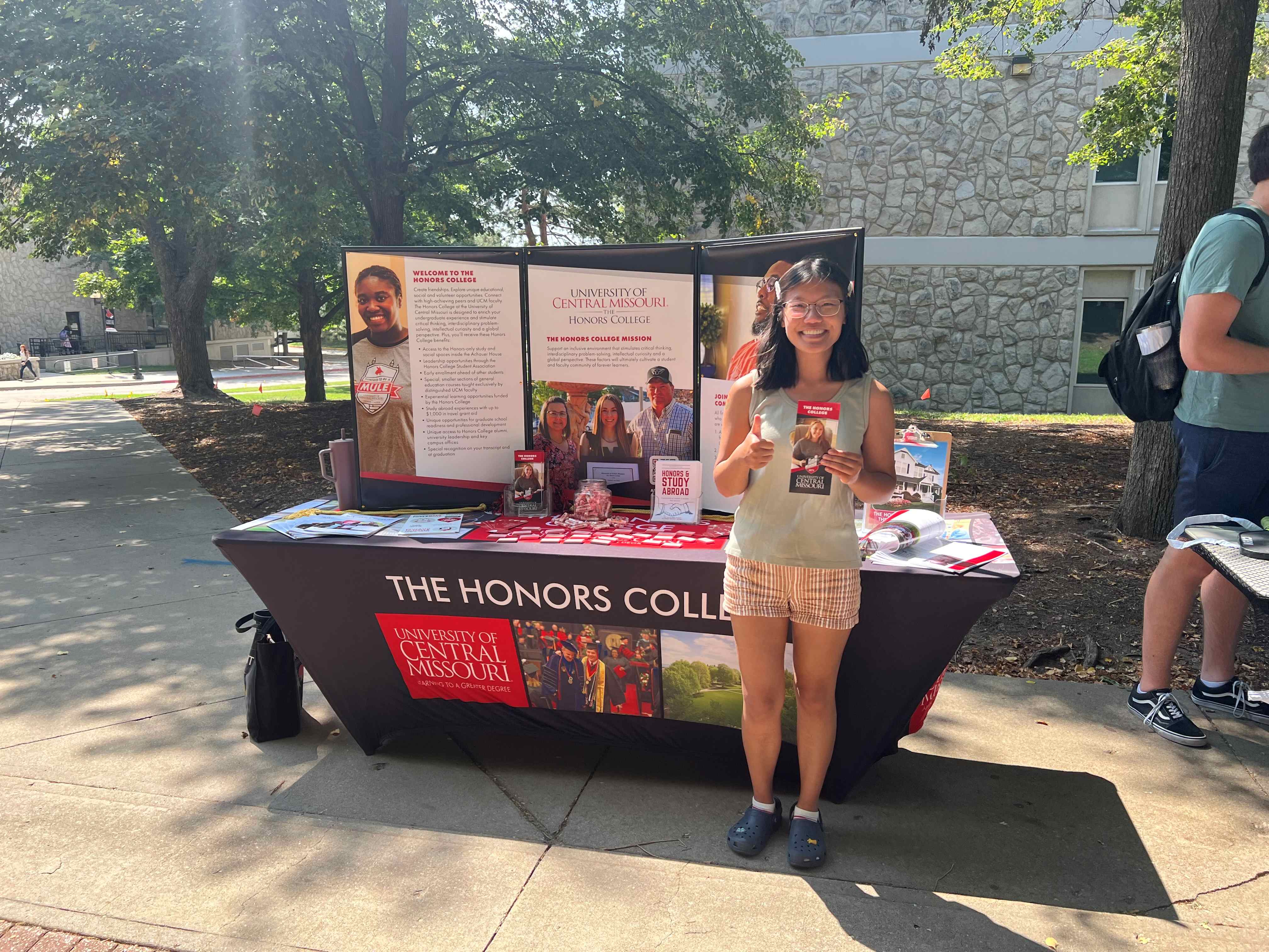 Honors student in front of pormotional table.