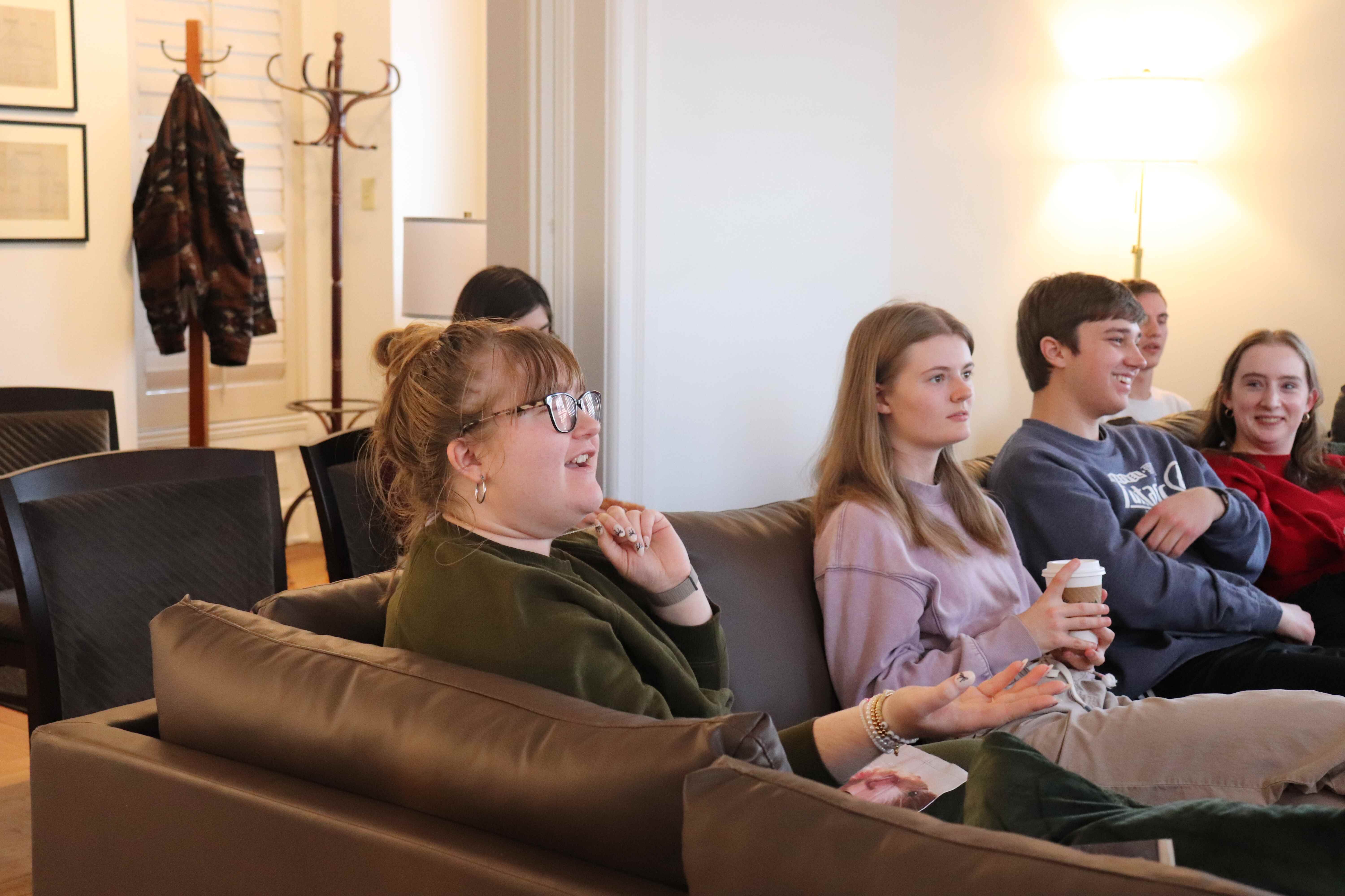 A group of honors students sitting on a couch watching presentations.