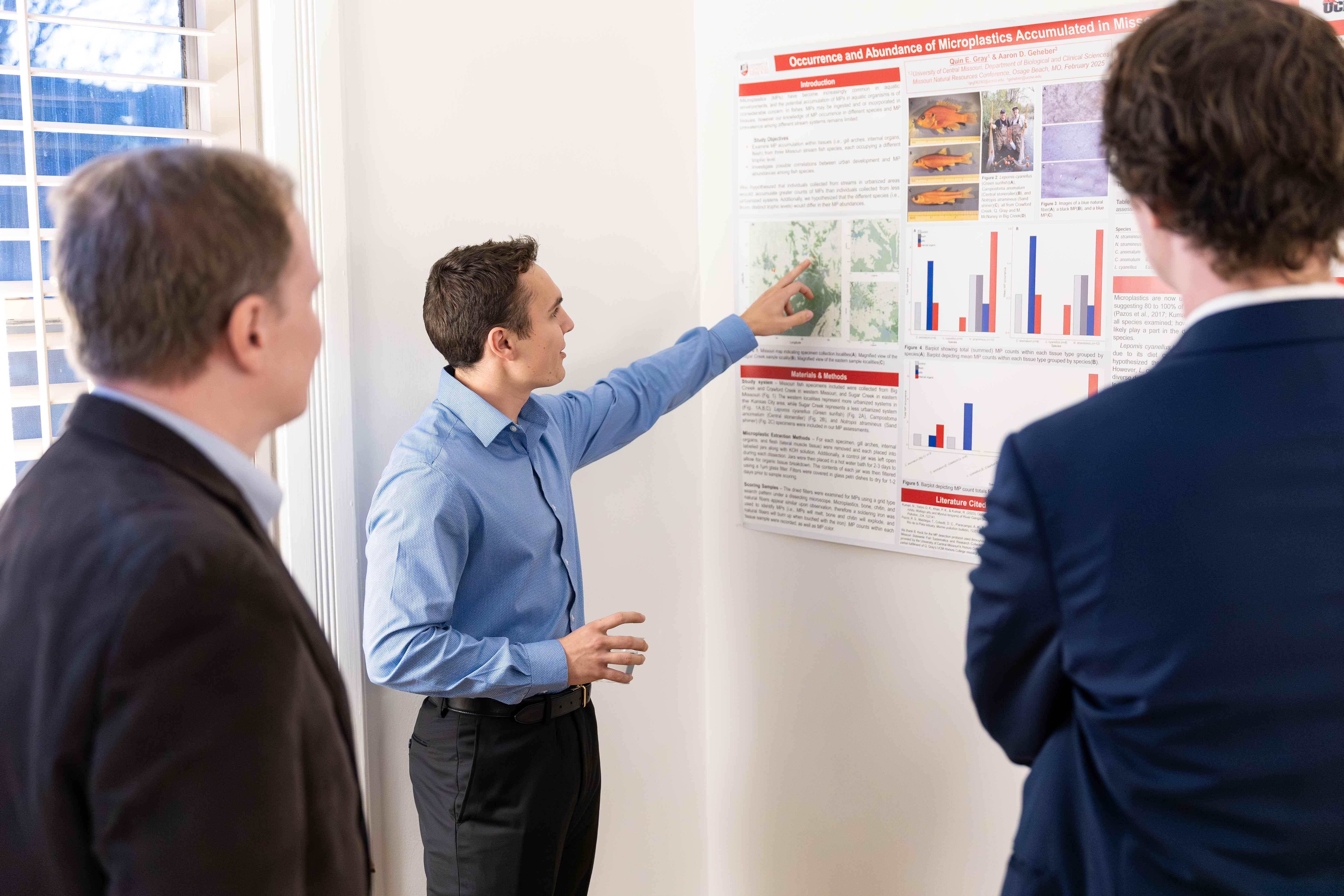 Honors student presenting their poster to two individuals.