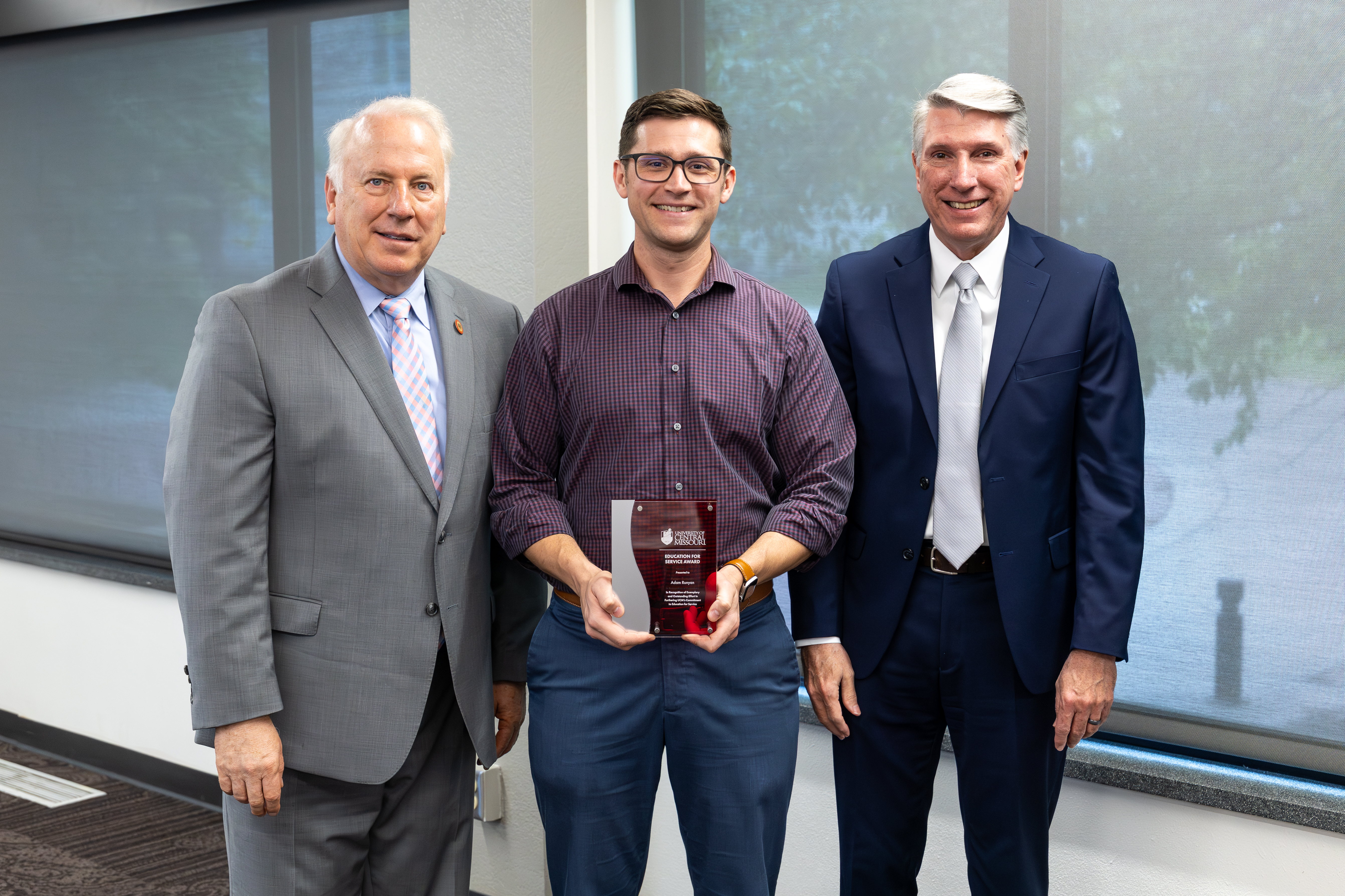 Flanked by UCM Board of Governors President John Collier, left, and UCM President Roger Best, Dr. Adam Runyon received the faculty Education for Service Award at the April 2026 Board of Governors meeting in Warrensburg.
